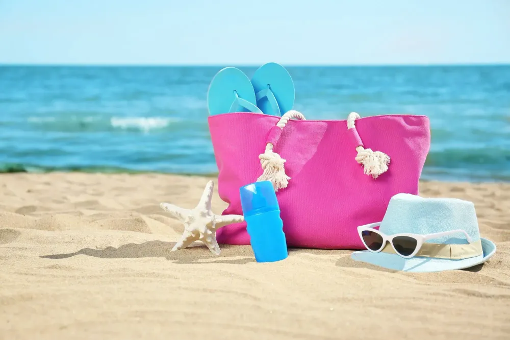 Pink beach bag with blue accessories on the beach